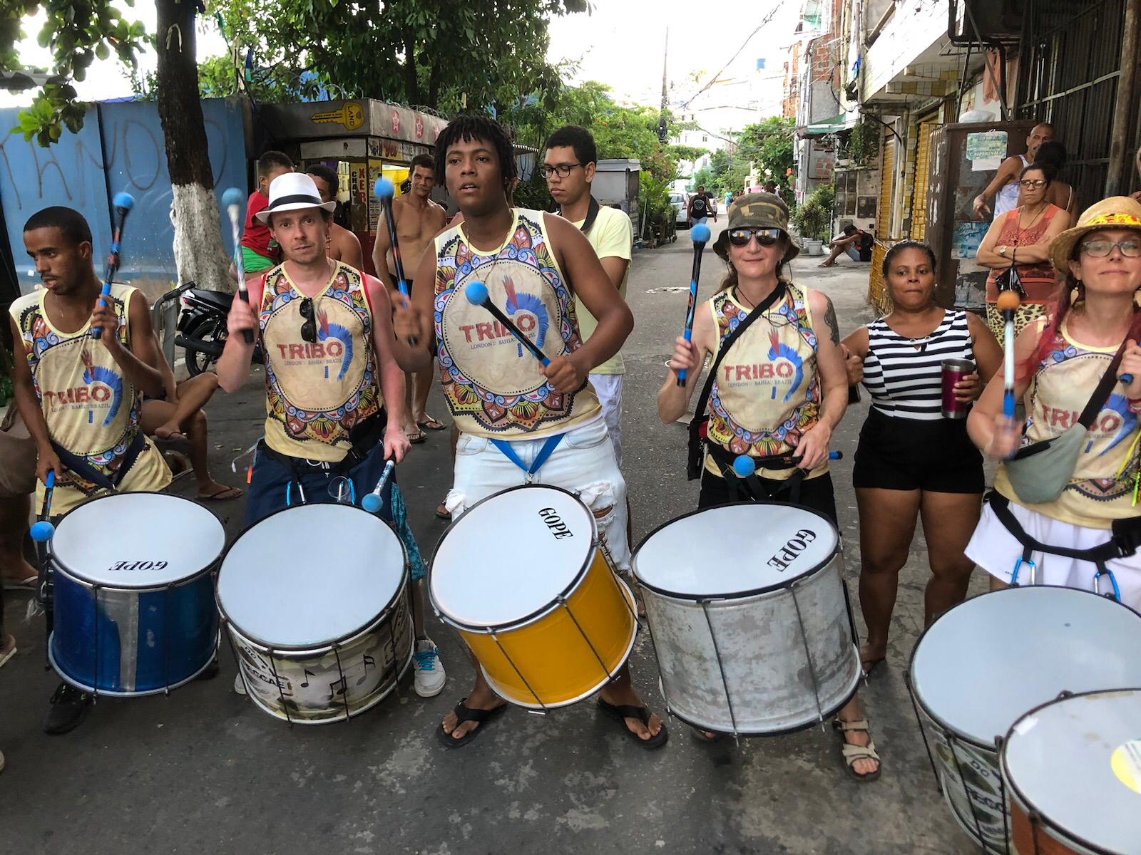 Tribo drummers in branded kit playing surdos in a Bahian street