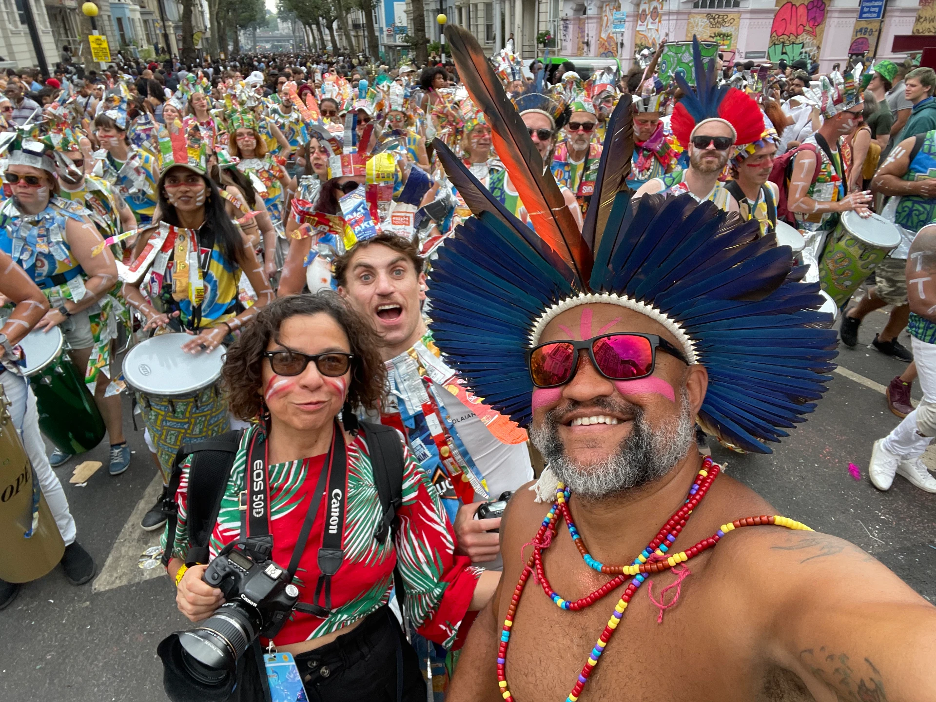 Marcos Santana in feather headdress at Notting Hill Carnival surrounded by drummers