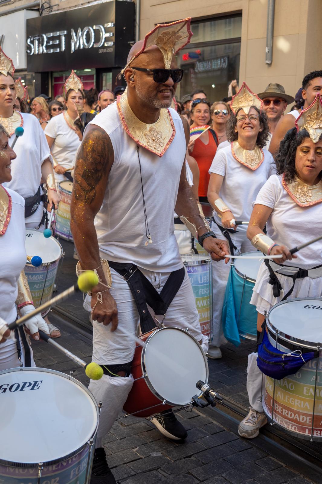 Marcos Santana conducting a large percussion ensemble through the streets at Marseille Pride